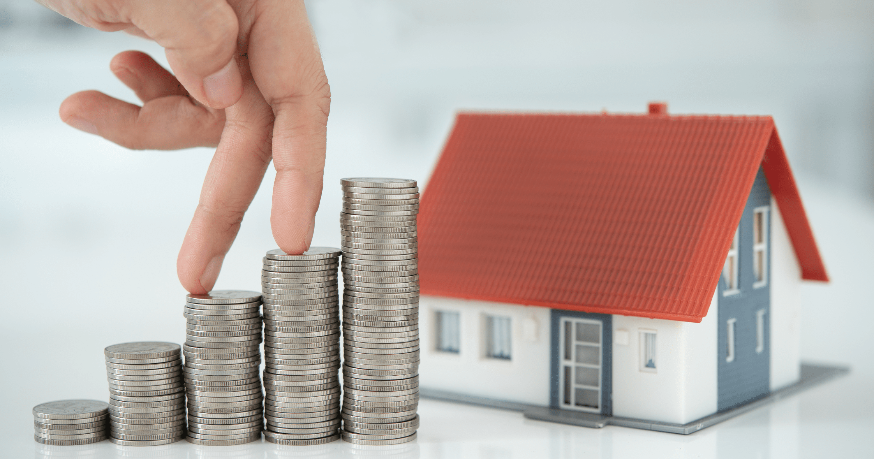 A stock image of a model home & stacks of coins - start your search for a Shared Ownership home on Share to Buy!