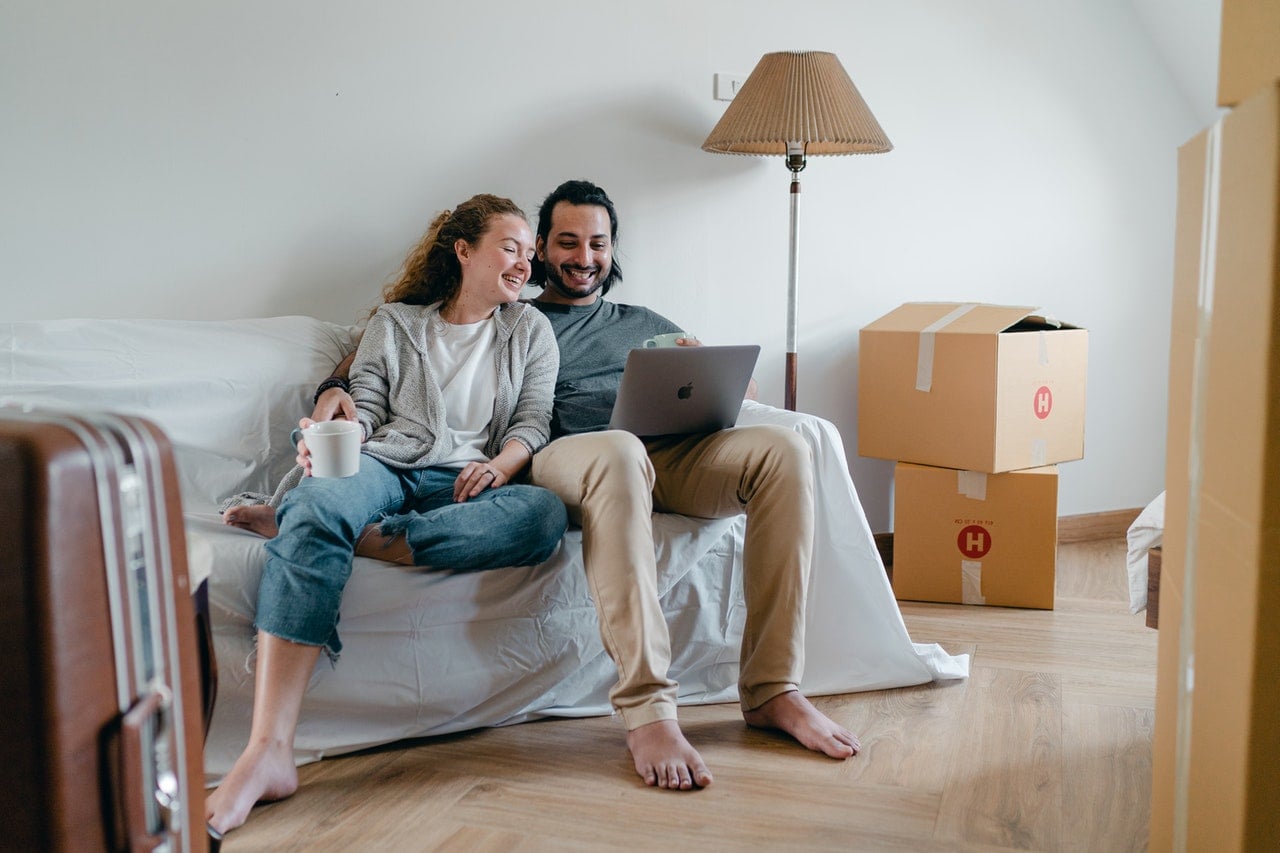 Stock image of a couple using a laptop and moving into a house - Start your property journey on Share to Buy!