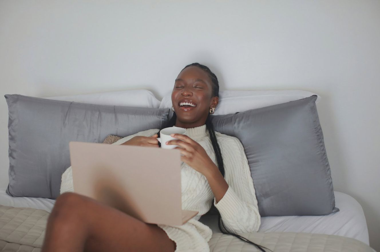 Young woman on laptop at home, sat on bed