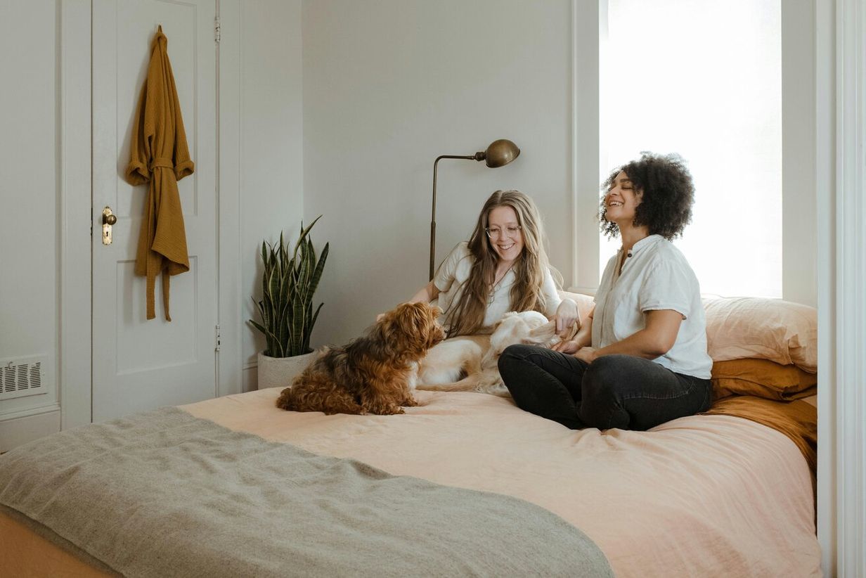 Two ladies and a dog having a laugh in their bedroom