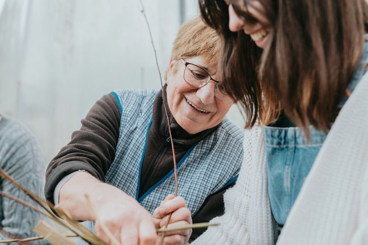 Older woman smiles and gardens with her adult daughter