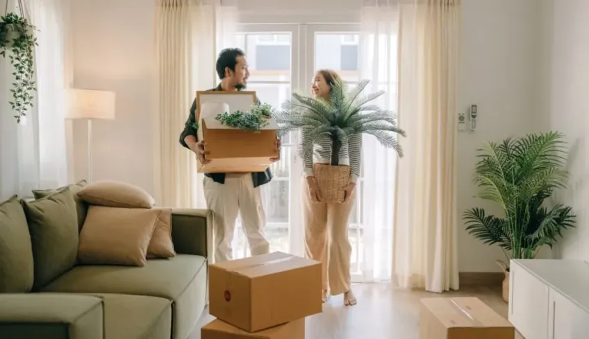 people carrying boxes to move house in a living room