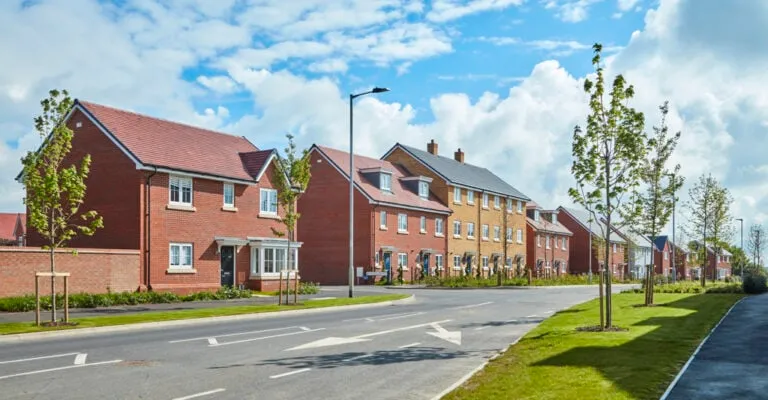 outdoor view of a street of new build houses with a road and some green spaces