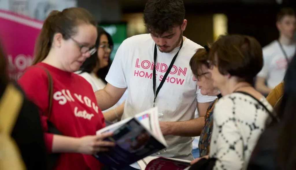 group of people at the london home show looking at brochures