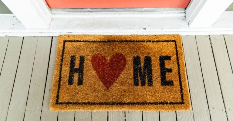 door mat with home written across the o replaced with a heart icon