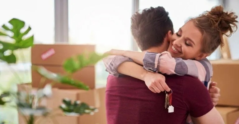 couple hugging in their new home holding keys to the house