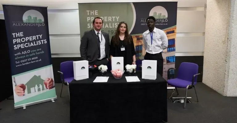 three people standing around a table with signs in the back