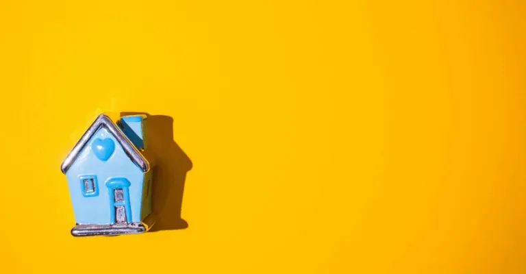 yelow background with small blue house figurine