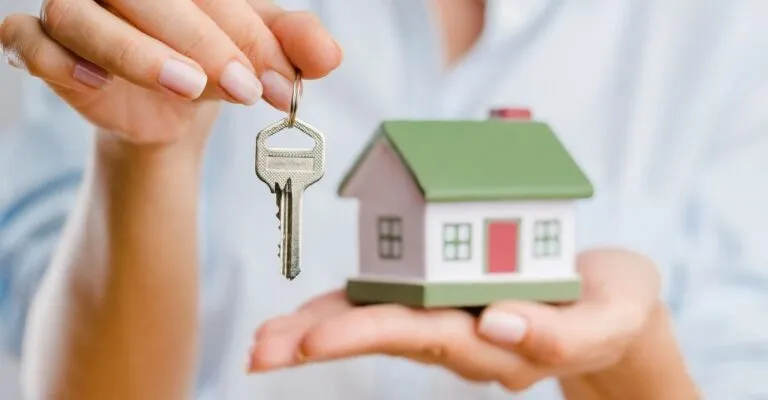 woman holding a key and a miniature figurine house