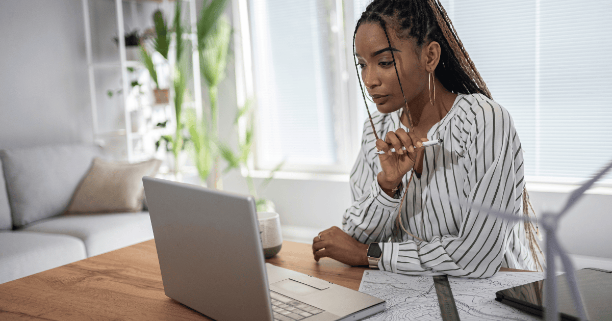 Woman sat at a table using her laptop in her living room.