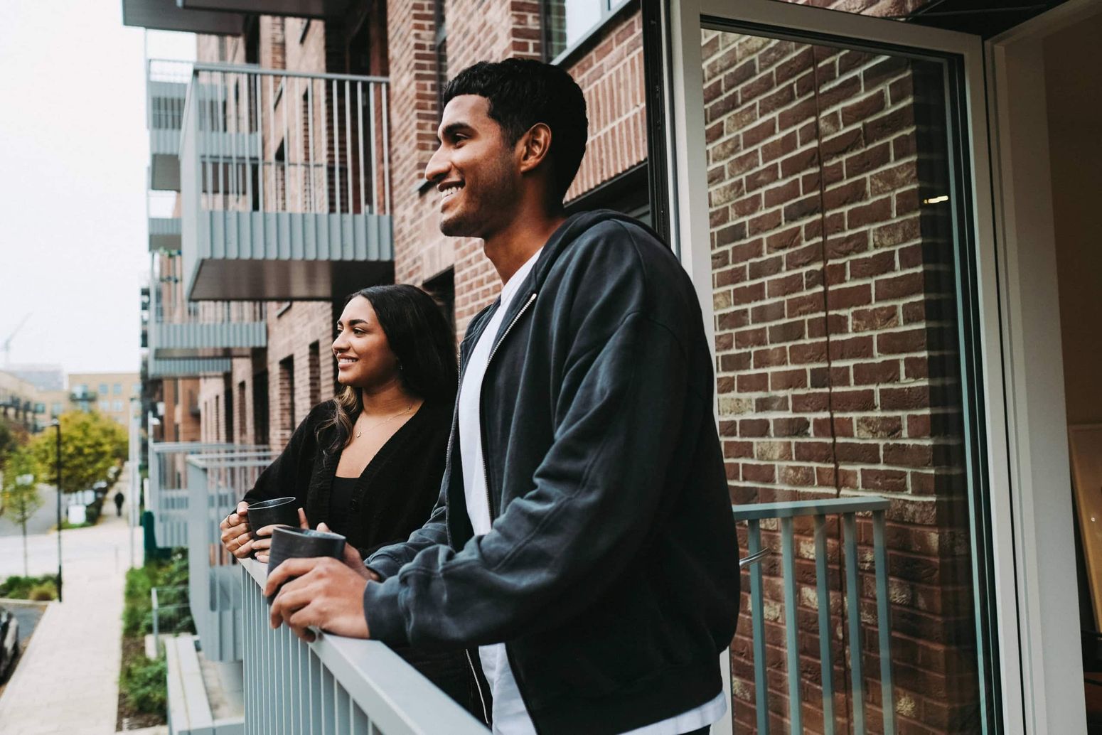 Man and woman standing on a balcony in an apartment at a Southern New Homes development.