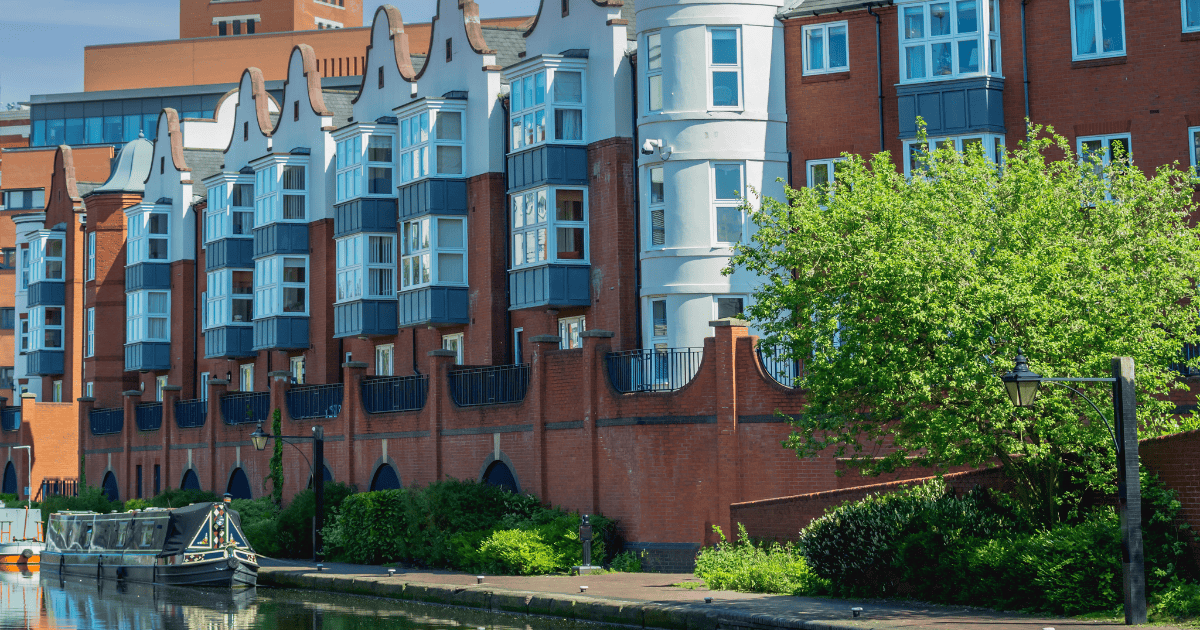 An apartment building in Birmingham overlooking a canal with two boats.