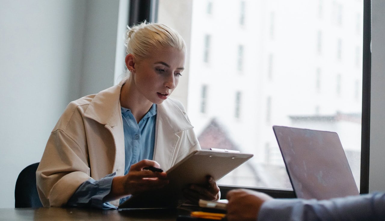 A young woman reviewing some paperwork on a clipboard.