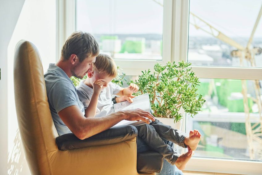 Male single parent reading book with son