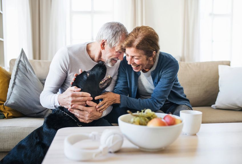 Couple at home on the sofa with their pet dog.